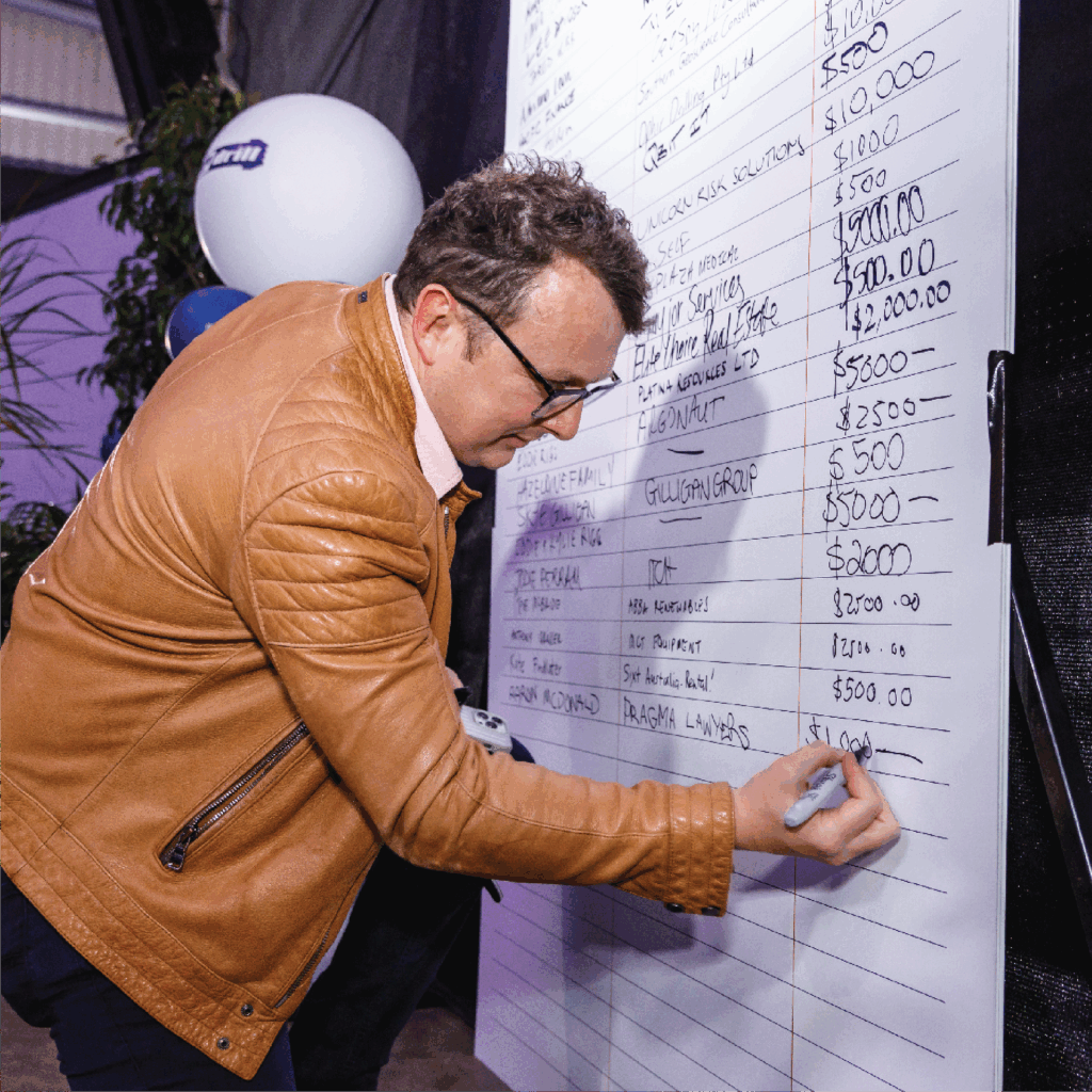 Man donating on pledge board at Resources Industry Charity Sundowner